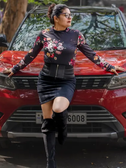 Leaning against the car, this pose highlights the corset belt that cinches the waist and adds structure to the outfit.