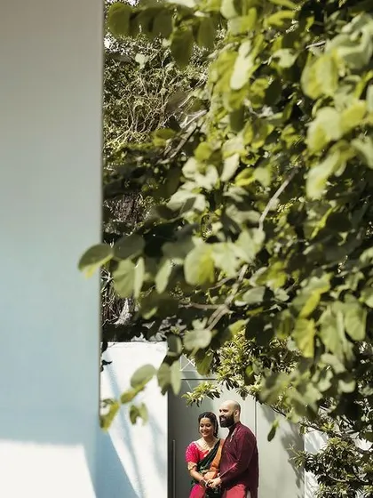 An artistic, framed shot of a couple in a garden. I use compositional techniques like framing to add layers and visual interest to your pre-wedding photos.