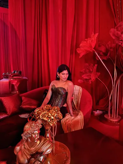 Taking a seat at the Gaurav Gupta show. The whole venue was bathed in this dramatic red light, and the decor was opulent. I styled myself in a black and gold corset with black trousers.