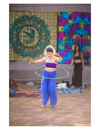 A hula-hooper in action, framed against the colorful backdrop of the festival grounds.