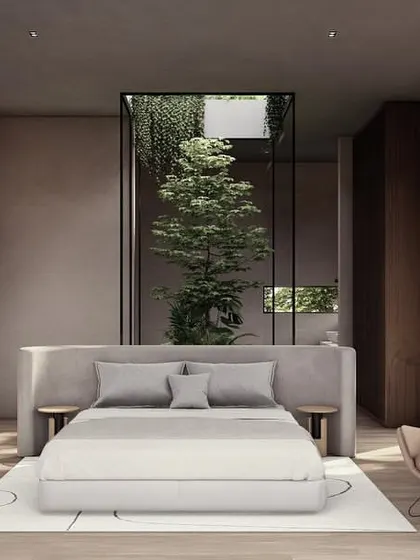 This bedroom in the Moira homes features a bed with a custom headboard that backs onto a glass-enclosed courtyard. This design brings a pocket of nature right into the room, enhancing the feeling of tranquility.