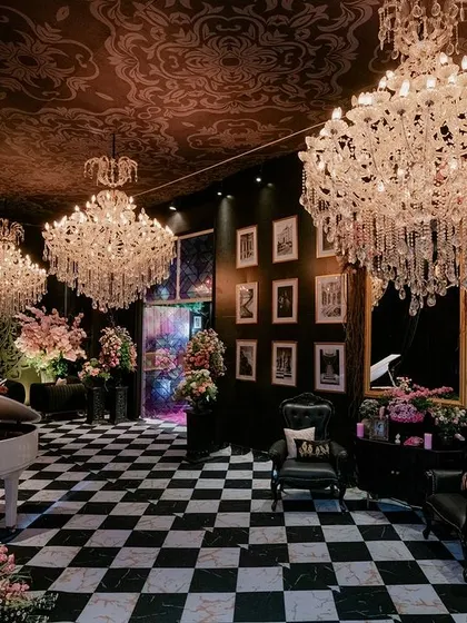 Another view of the grand piano entrance, showing the dramatic contrast between the dark, patterned ceiling and the sparkling crystal chandeliers.