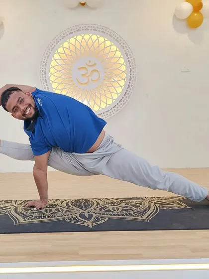 A smiling student holds an advanced side plank variation, demonstrating both strength and joy in the practice.