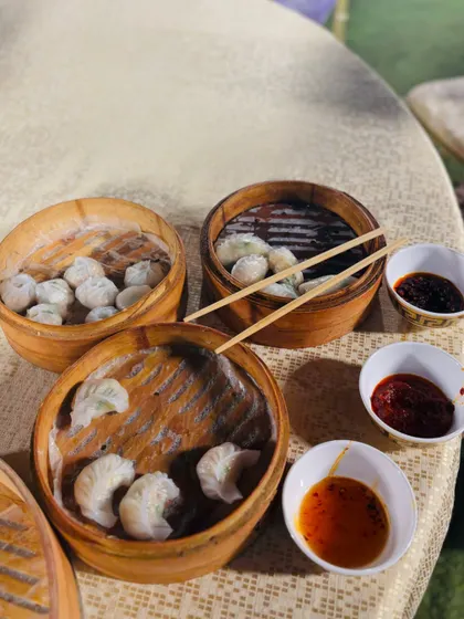 A selection of freshly steamed dim sum served in traditional bamboo baskets, complete with a variety of dipping sauces.