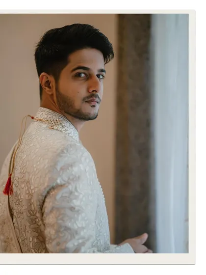 A classic groom portrait by the window, capturing his thoughtful expression as he looks back.