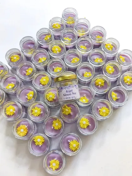 A diamond-shaped arrangement of mini jar candles with yellow flower toppers, made for a baby announcement.