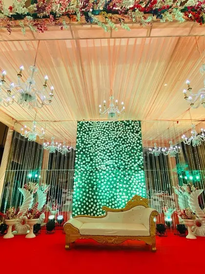 A centered shot of the indoor stage with the green floral wall, showing the beautiful ceiling and lighting of the venue.