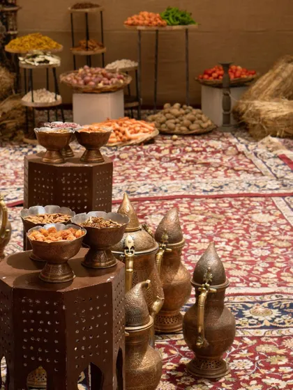 Traditional copper vessels and bowls filled with dried fruits were arranged on intricate carpets, creating a rich and authentic tablescape.
