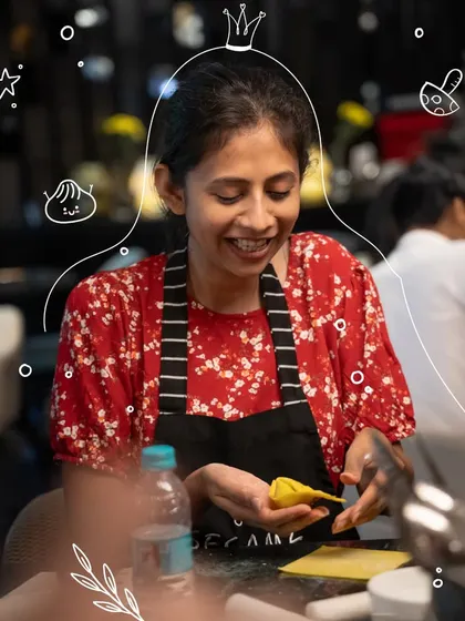 A participant smiles as she successfully folds her first dim sum. The hands-on nature of our workshops means you're actively learning and creating.
