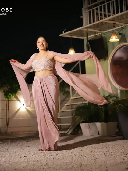 This client looks absolutely graceful in a draped, Indo-western style gown. The unique silhouette and soft color make it a sophisticated choice.