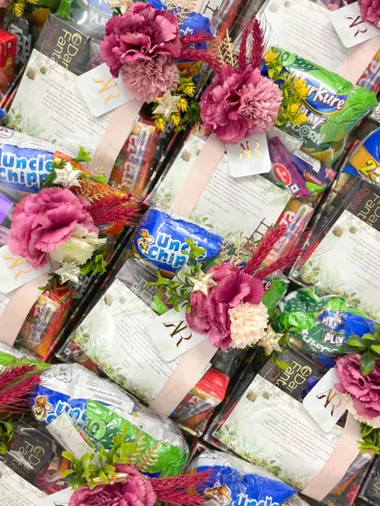 An overhead view of the room hampers, showing the colorful assortment of popular Indian snacks and drinks. The custom tags with the couple's monogram add a personal touch.