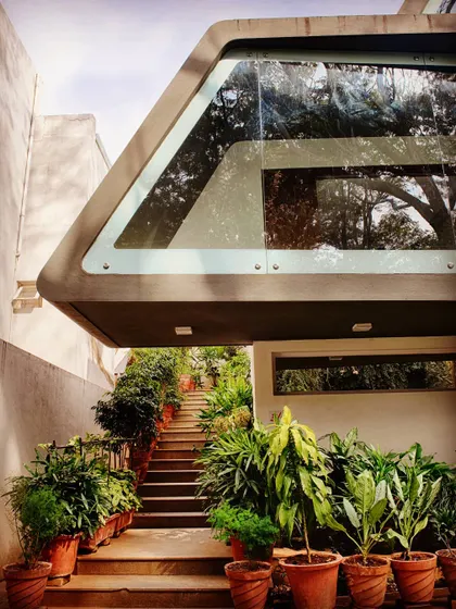 A view of the single-flight staircase leading up to the cantilevered canopy of the Mobius Home. The design uses lush greenery along the path to create a tranquil transition from the ground level.