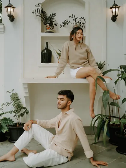A stylish, relaxed portrait taken at a villa in Goa. The neutral-toned outfits and lush green plants create a modern and serene aesthetic for this pre-wedding shot.