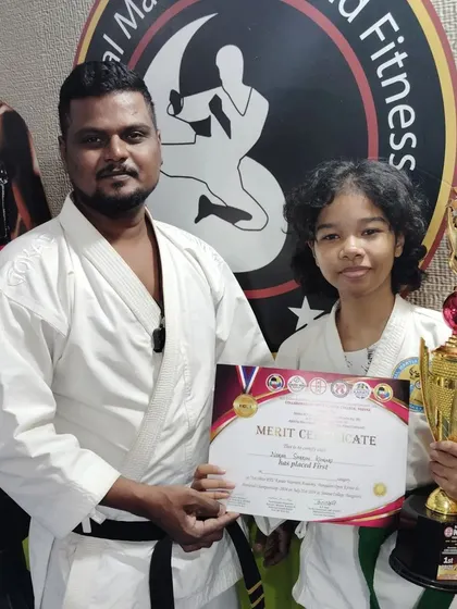 A green belt student with her first-place trophy, celebrating her success in the karate championship.
