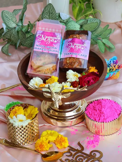 A beautifully styled shot of our Holi offerings, including baked gujia and thandai cake, presented in an elegant deer-handled bowl.