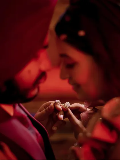 The intimate moment of the ring exchange, captured with dramatic red lighting.