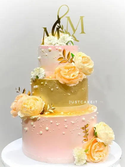 This elegant three-tier wedding cake features a beautiful blend of peach and gold tones, adorned with delicate sugar flowers. It’s a perfect example of how I create stunning, eggless centerpieces for your most special day, built sturdy enough to travel anywhere in Mumbai.