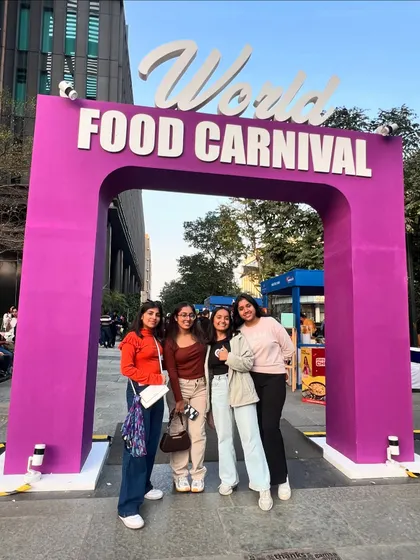 Friends gather for a photo at the World Food Carnival entrance, ready to explore the global feast. It's all about making memories together.