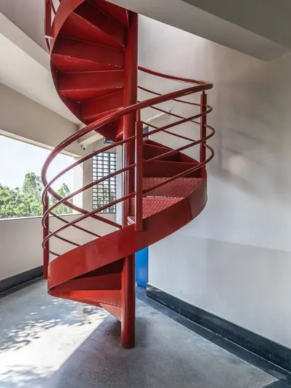 A vibrant red spiral staircase serves as a sculptural focal point at L'Atelier, the art school at Greenwood High Campus. It is a functional element that also injects energy and creative spirit into the space.