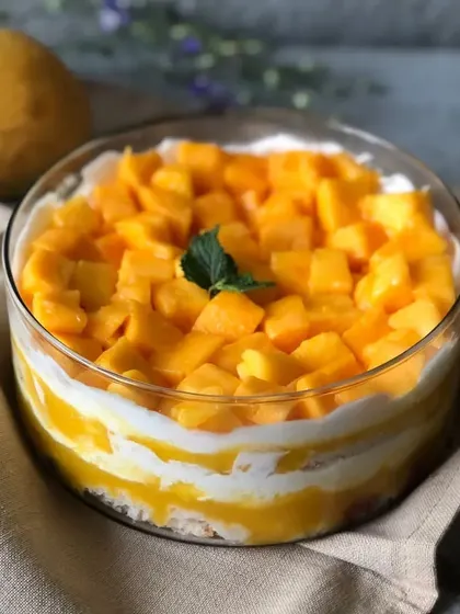 A beautiful shot of our Mango Cream Cheese Trifle, topped with fresh mango chunks and a mint leaf, ready to be enjoyed.