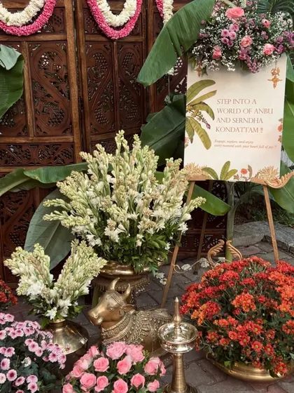 A close-up of a welcome setup for a South Indian event, featuring brass decor and colorful flowers.