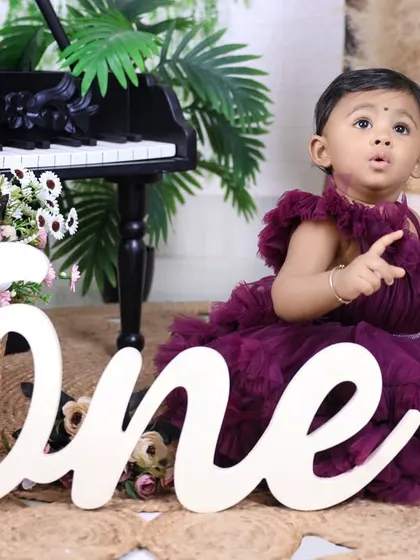 A candid shot capturing the little girl's expressive face during her first birthday photoshoot. These unposed moments are often the most cherished.