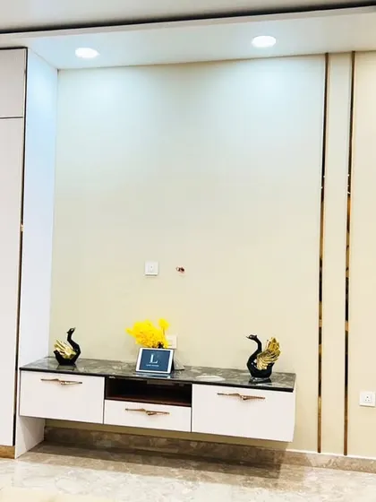 The TV and console unit in this bedroom is sleek and minimalist, with a combination of white marble and high-gloss finishes. The gold-toned inlay on the wall adds a subtle touch of glamour.