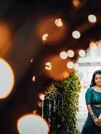 A beautiful reception photo with the couple framed by dreamy bokeh lights, holding hands and sharing a smile.