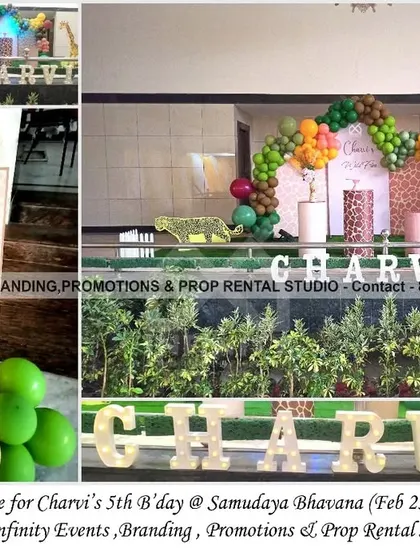 A charming giraffe theme for a 5th birthday at Samudaya Bhavana. The setup includes a printed backdrop with a balloon arch, giraffe-print cylinder props, and large marquee letters, creating a fun and wild party atmosphere.