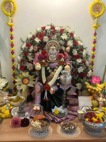 This deity is draped in a soft mauve silk saree, surrounded by an arch of red and white roses for the festival.