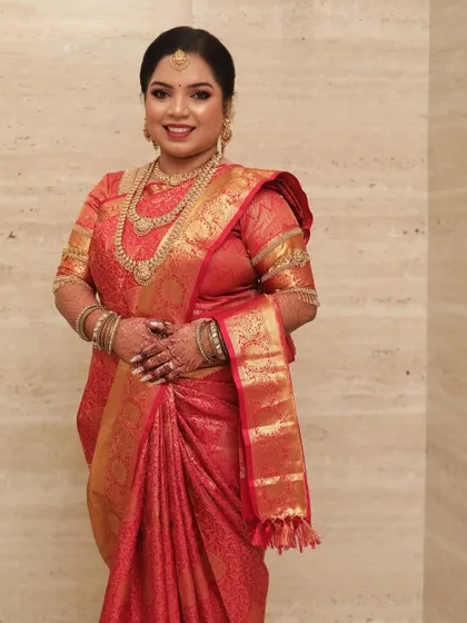A South Indian bride in a rich red silk saree, looking radiant and happy.