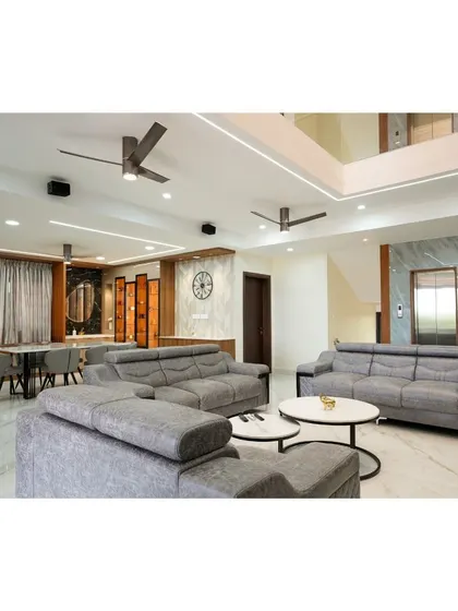Another perspective of the villa's living room, highlighting the interplay between the seating arrangement, the dining area in the background, and the architectural element of the open staircase.
