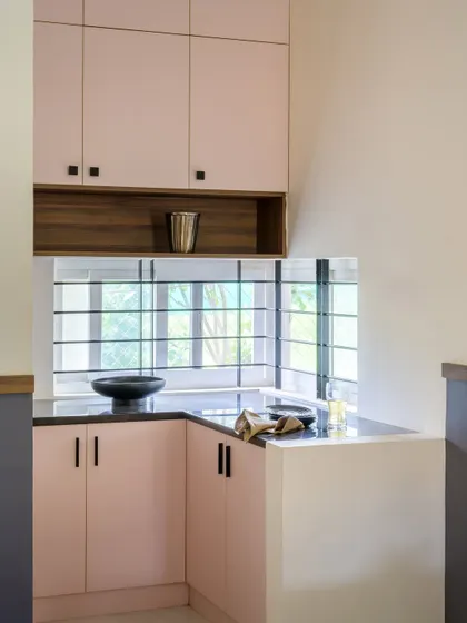 A different angle of the pantry, showing the corner window that brings in natural light. The combination of pink, wood, and black creates a modern and chic look.
