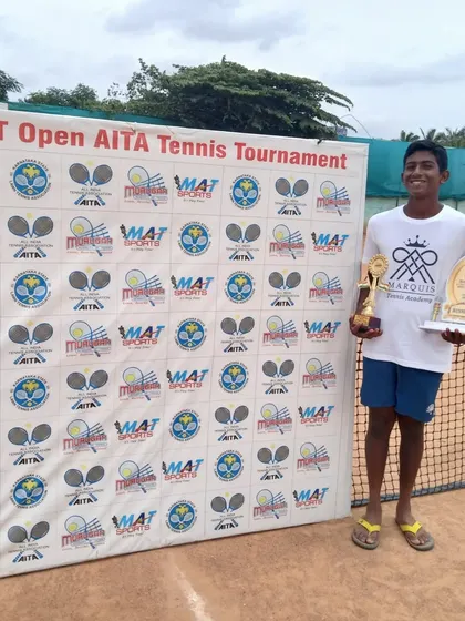 A successful outing at the MAT Open AITA Tennis Tournament. This player's smile shows the joy that comes from dedicated effort and achieving results on the court.