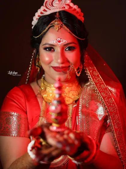 A classic portrait of a Bengali bride holding the traditional sindoor box. Her direct gaze and gentle smile create a powerful and engaging image.