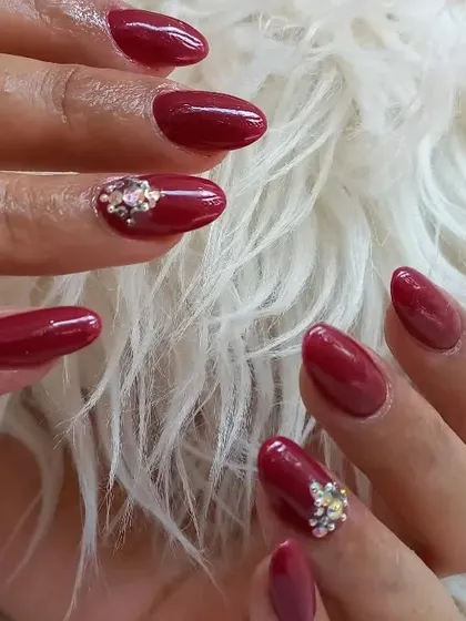 A classic deep red manicure with a glamorous twist. Accent nails feature a beautiful cluster of iridescent rhinestones.