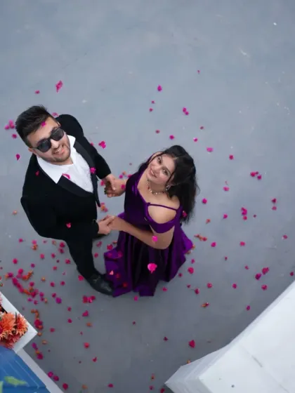 A shower of petals for a happy couple. This aerial shot captures a beautiful moment, showcasing their coordinated purple and black outfits from a unique perspective.