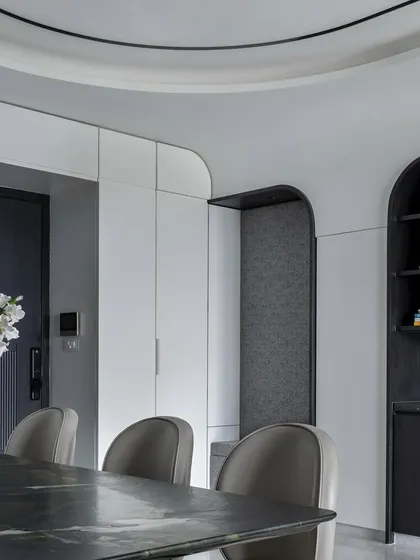 The dining and storage area in 'The House of Arcs' features custom cabinetry with arched niches, continuing the home's central design theme.
