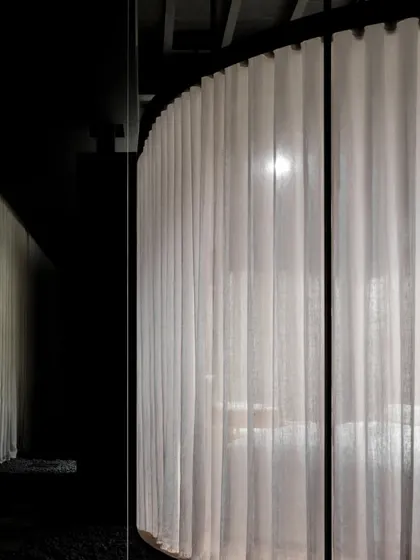 A close-up view highlights the ephemeral quality of the sheer curtains. This material choice was critical for its ability to filter and soften light, lending a sense of transparency and quiet elegance while defining the boundaries of the space.