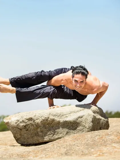 Taking our practice outdoors connects us with nature. This advanced arm balance, Eka Pada Koundinyasana II, requires immense core strength and focus, showing the peak of physical discipline.