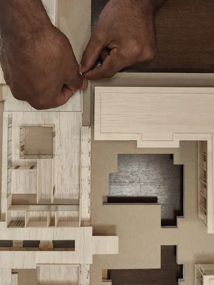 The delicate process of assembling a physical model. This top-down view reveals the plan of the building in three dimensions, showing the relationship between different spaces.