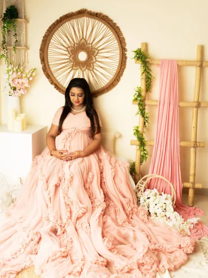 A full-length portrait in a peach ruffled gown, seated in the boho-chic corner of my studio. The setting is perfect for a soft, feminine look.