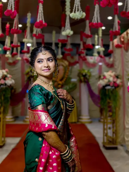 The bride stands amidst the floral decor of the wedding hall, her expression thoughtful and serene.