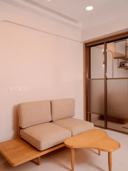 A compact seating area with a custom wooden sofa and organic-shaped coffee table, demonstrating our ability to create functional and stylish minimalist furniture.