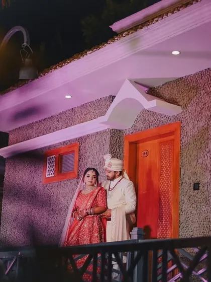 A full-length shot of the couple outside their wedding venue at night. The ambient lighting creates a romantic and slightly dramatic mood for this portrait.