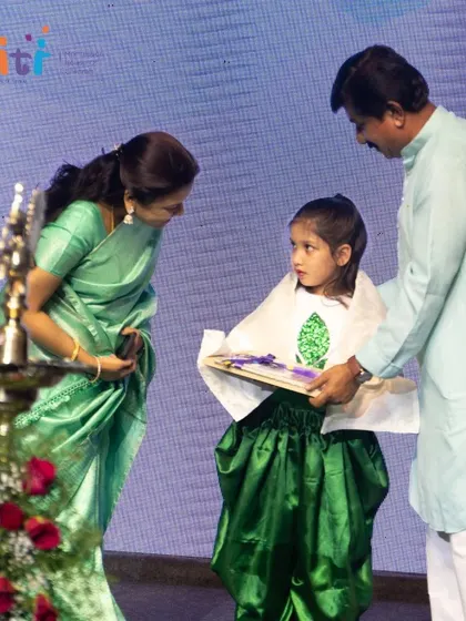 A girl in her performance costume receives her graduation certificate, marking a dual celebration of her achievements.