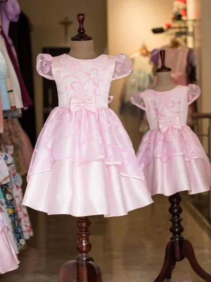A third shot of these popular matching pink dresses, perfect for any parent looking to create a memorable twinning moment for their daughters.
