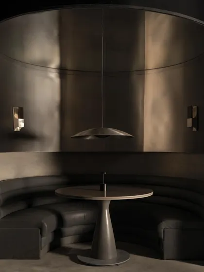 The main dining area of Lair, where curved metal partitions create semi-private booths. The reflective surfaces create a disorienting yet captivating play of light and shadow.