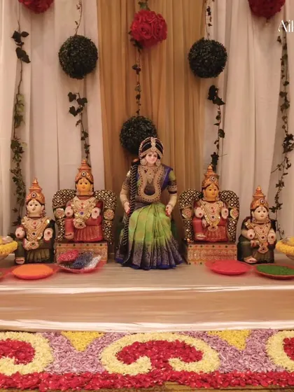 A divine setup for a pooja, featuring beautifully dressed 'Pattada Gombe' (dolls). The backdrop is made of marigold and tuberose flowers, creating a sacred space for the ceremony.