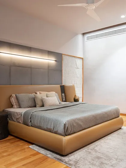 Another bedroom in the residence, featuring a custom-designed bed with a unique leather and fabric headboard. A sleek, linear wall light provides ambient illumination.